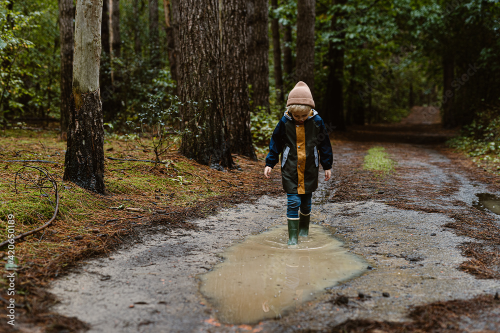 Little blond toddler boy playing in a rain puddle Little blond toddler boy playing in a rain puddle