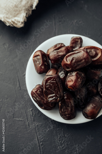 traditional iftar evening snack in the fast of Ramadan. dried dates on farvor plate on dark background top view. traditional oriental sweets. healthy natural snack. vertical, selective focus photo