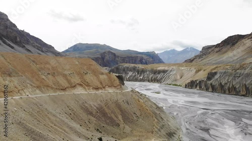 Following a curvy, mountainous road next to a wide empty river in the Himalayas photo