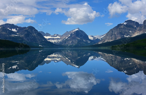 the reflection of  mountain peaks in glacier park national park, montana, in the mirrorlike surface of lake sherburne im the many glacier valley along the road to many glacier in the summer photo