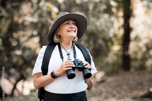 Active old woman using binoculars to see the beauty of nature photo