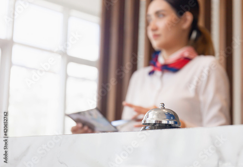 Bell at modern luxury hotel reception counter desk with blurred young woman receptionist standing at workplace