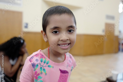 Happy and beautiful short hair preschool age girl enjoying different indoors children activities at a retreat while in remission from pediatric chemotherapy treatments