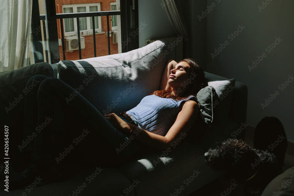 Young woman laying on her couch taking some sun. Young woman laying on her couch taking some sun.