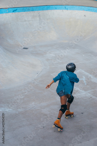 Cool African American woman drives roller skates in an open area photo