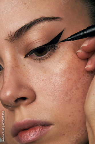 Woman With Freckles Applying Eyeliner photo