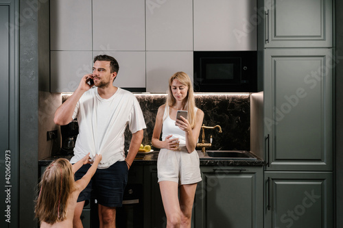 Parents using smartphones near little daughter
