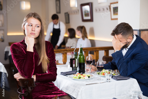 Depressed couple sitting at restaurant unhappy after quarrel on date