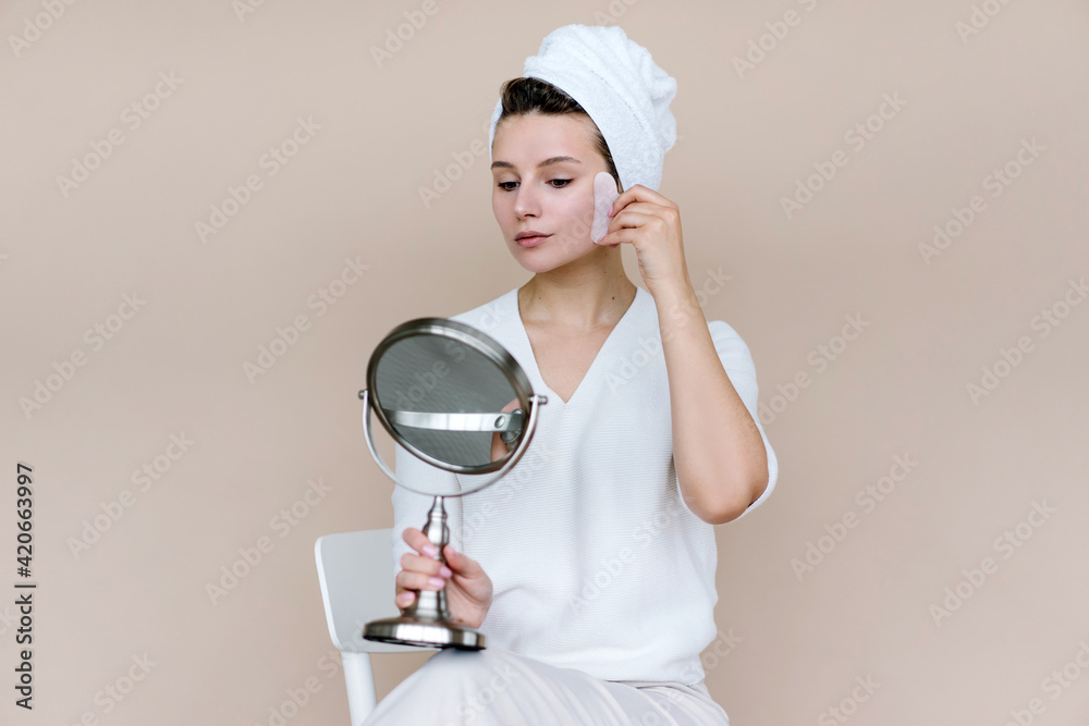 Woman doing facial massage with stone in bathroom Woman doing facial massage with stone in bathroom
