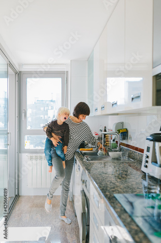 Mother with kid washing dishes in kitchen photo