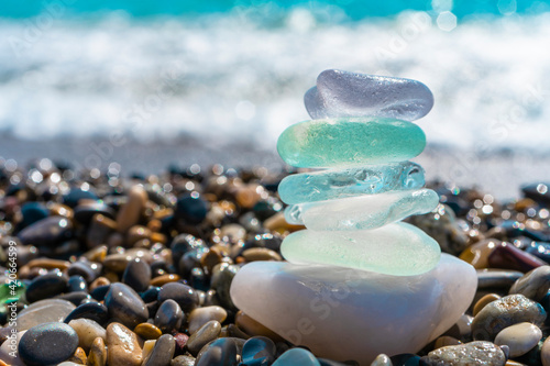 Canvas Print Sea glass stones arranged in a balance pyramid on the beach
