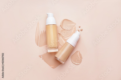 Bottles of makeup foundation and samples on color background