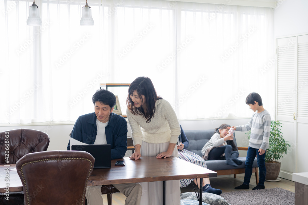 テレワークをする両親とリビングで過ごす子供たち テレワークをする両親とリビングで過ごす子供たち
