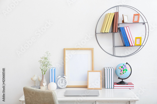Stylish workplace with laptop and bookshelf against light wall in room © Pixel-Shot