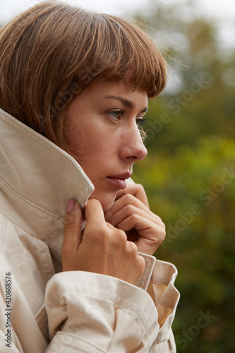 Woman standing outside holding her jacket lapel photo