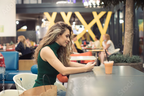 Young Woman sitting in a Food Court of Shopping Mall