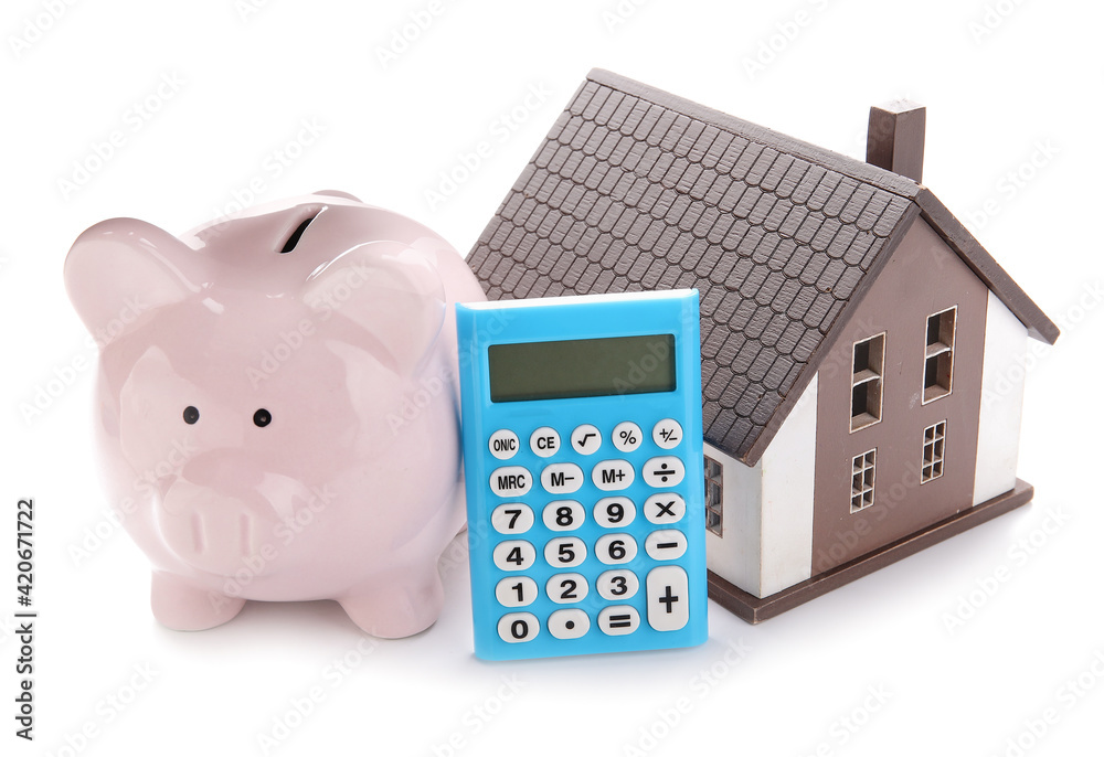 Calculator with model of house and piggy bank on white background