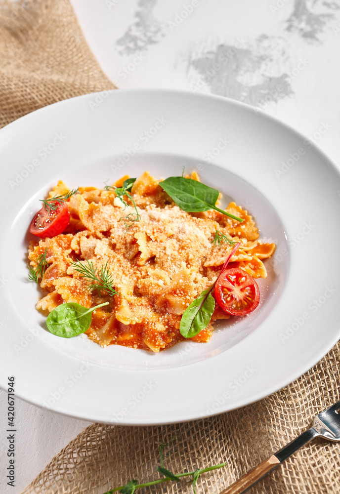 Farfalle pasta food on white table. Pasta restaurant plate with basil leaf and tomato, red tomato sauce. Delicious italian pasta. Farfalle pasta food on white table. Pasta restaurant plate with basil leaf and tomato, red tomato sauce. Delicious italian pasta.