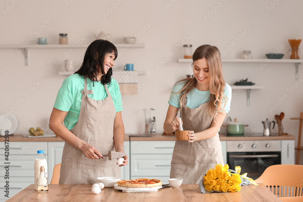 Young woman with her mother cooking pizza at home