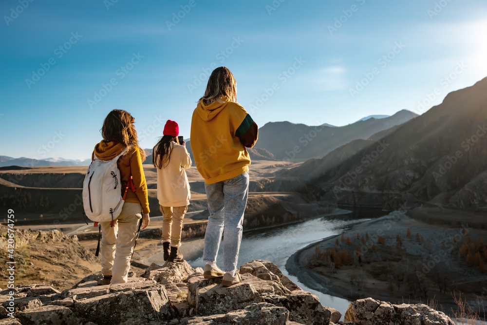 Three female hikers or tourists in sunset mountains