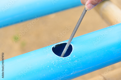 The man use rasp scratch the hole at blue PVC pipe