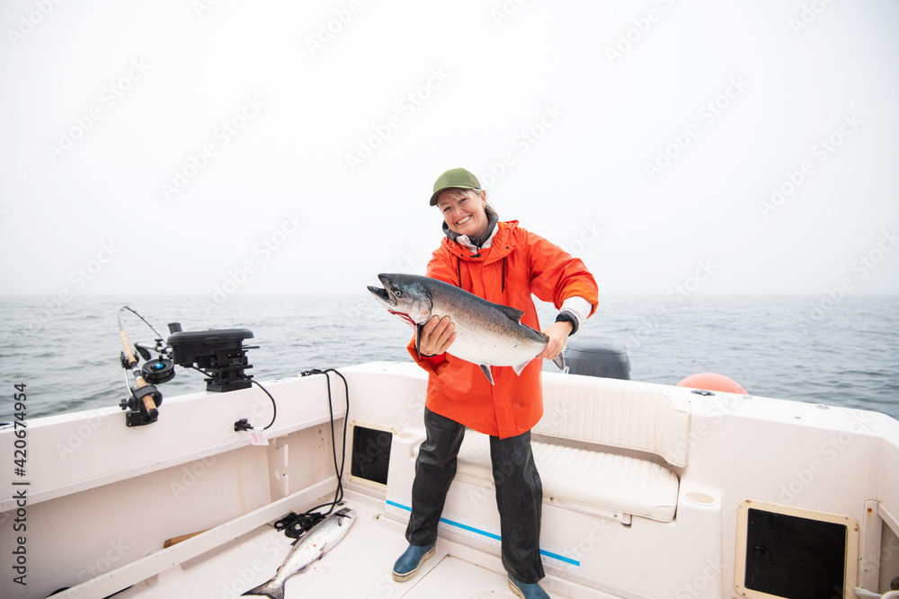 Woman holding a fresh salmon on a boat in the ocean Woman holding a fresh salmon on a boat in the ocean