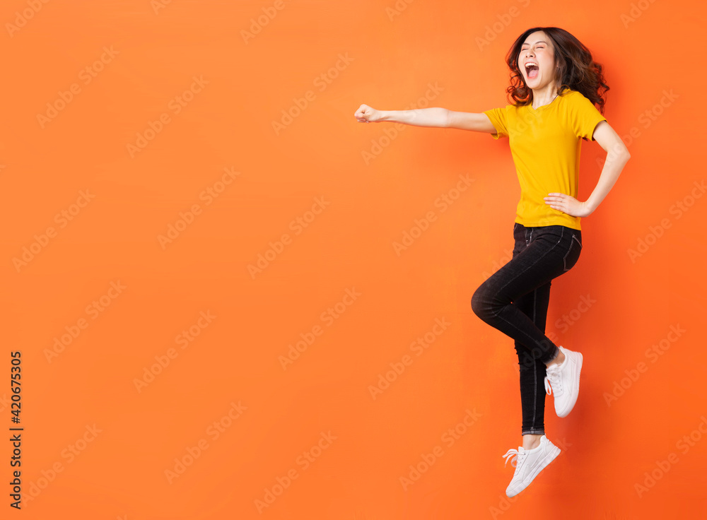Young asian girl jumping up on orange background