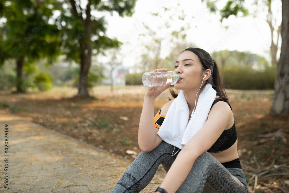 Fitness woman taking a break after running workout and drinking water from plastic bottle. Fitness woman taking a break after running workout and drinking water from plastic bottle.