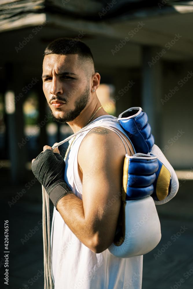 Serious man with boxing gloves in city Serious man with boxing gloves in city