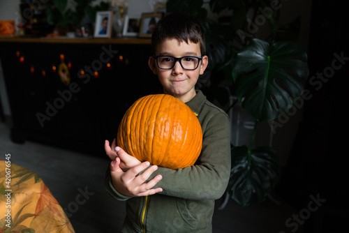 Little boy holding a big pumpkin on his arms