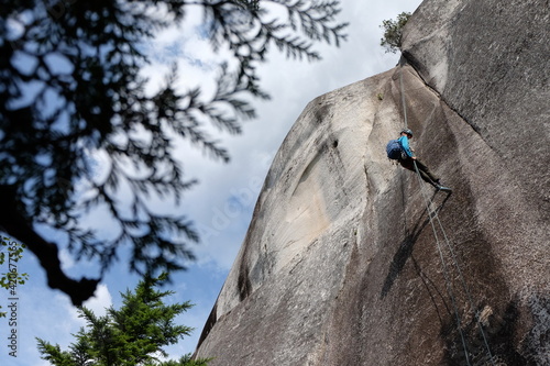 Man rappels down a granite cliff face. photo