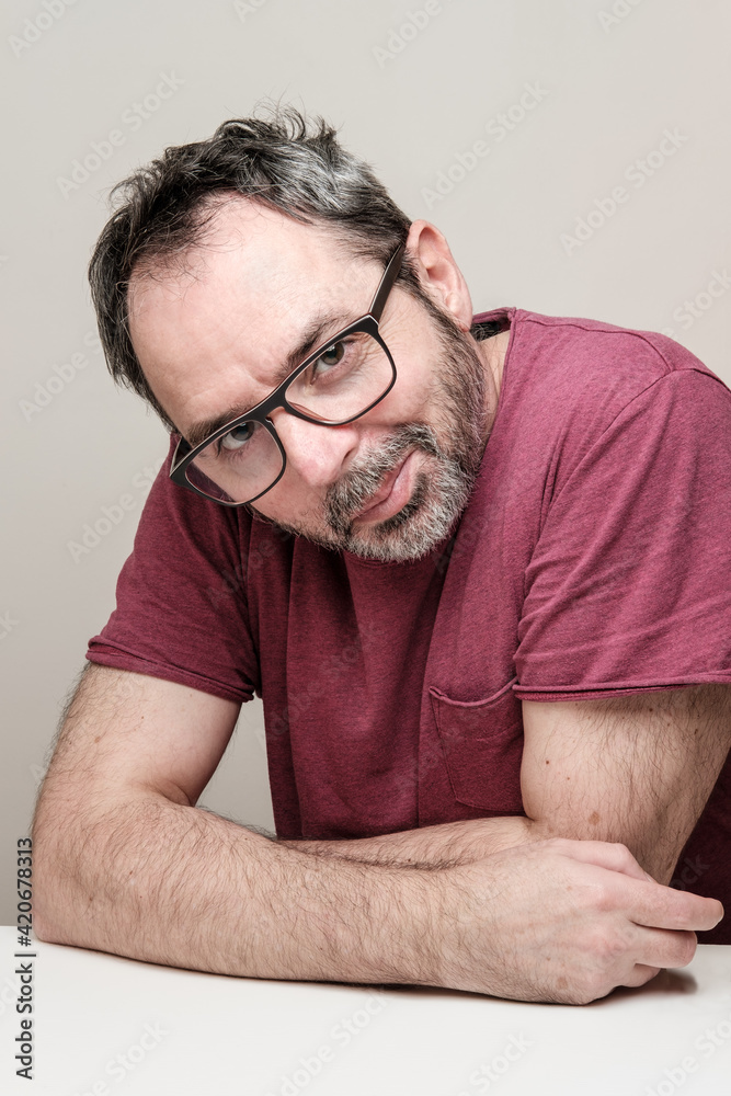 Obraz premium Portrait of a smiling mature man with bear wearing red t-shirt and glasses.