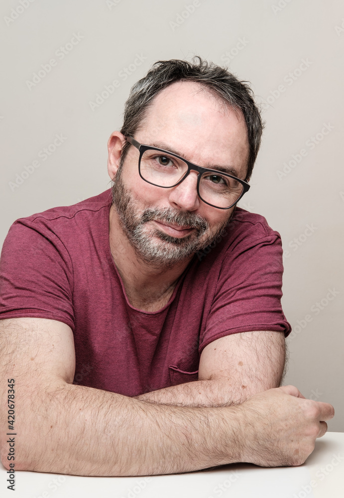 Obraz premium Portrait of a smiling mature man with bear wearing red t-shirt and glasses.