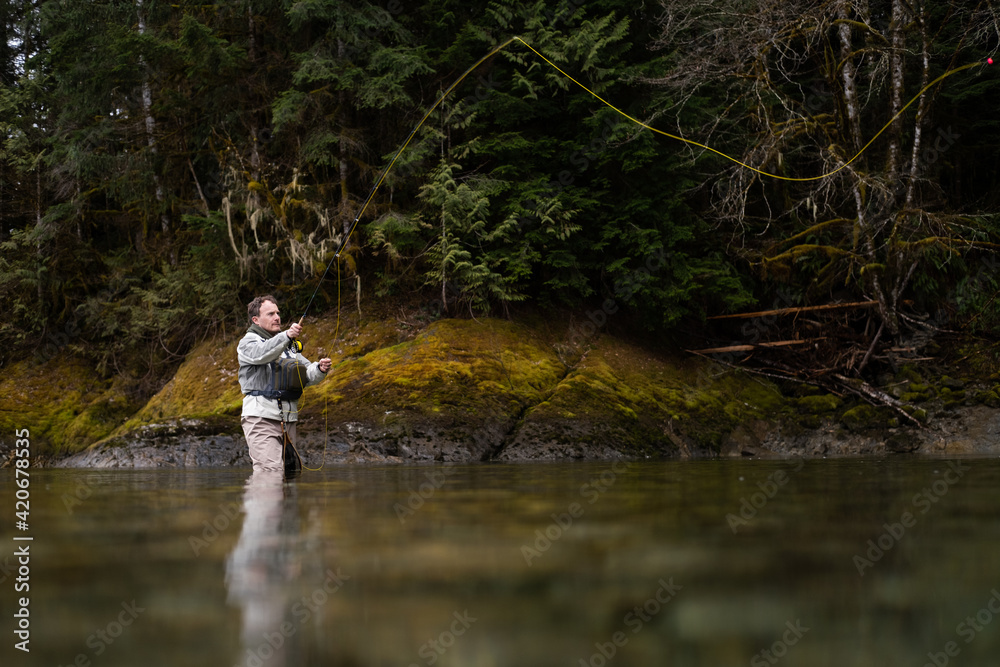Fly fisherman wearing hip waders fishes in a stream. Fly fisherman wearing hip waders fishes in a stream.