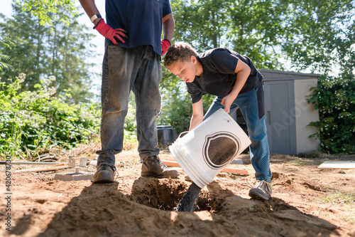 Boy pours bucket of gravel.