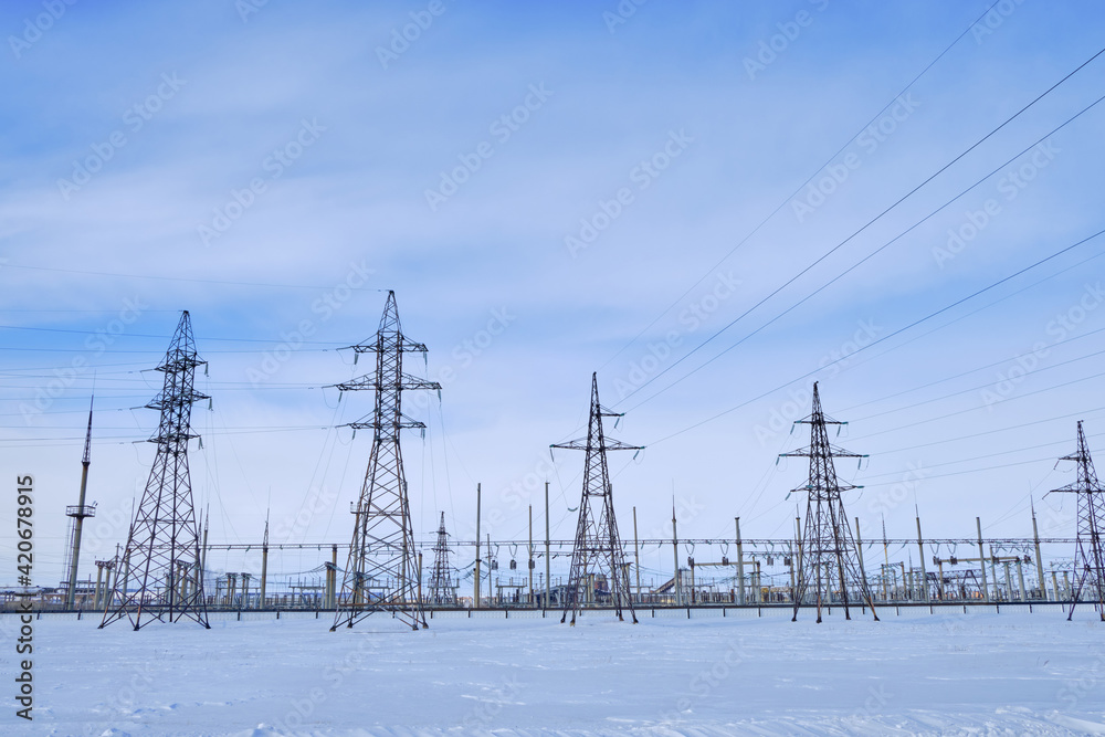 industrial landscape. High voltage towers with electrical wires on blue sky background. Electricity transmission lines, electric power station.

