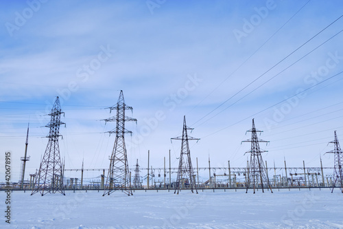 industrial landscape. High voltage towers with electrical wires on blue sky background. Electricity transmission lines, electric power station.