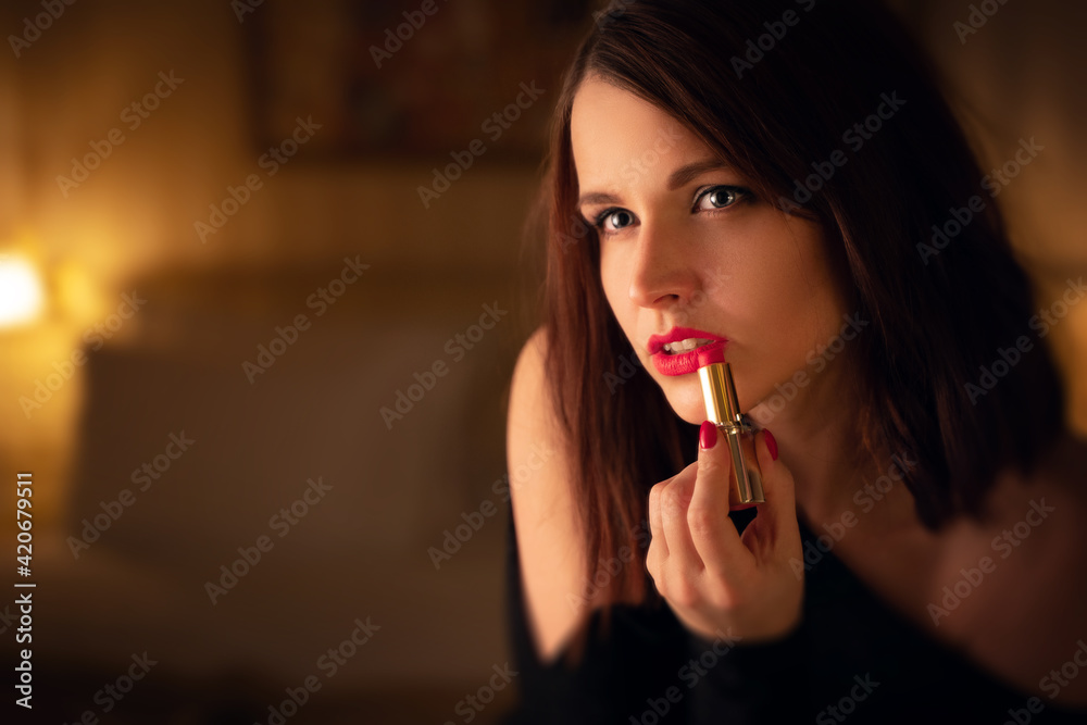 Young beautiful female brunette model applying her makeup making her red lips and hair ready Young beautiful female brunette model applying her makeup making her red lips and hair ready