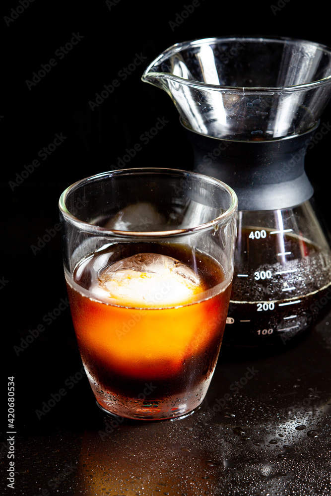 Cold americano decoration with ice ball in whisky glass on a black table. Cold americano decoration with ice ball in whisky glass on a black table.
