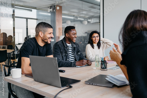 Group of multiracial businesspeople laughing and smiling during a meeting in modern workplace photo