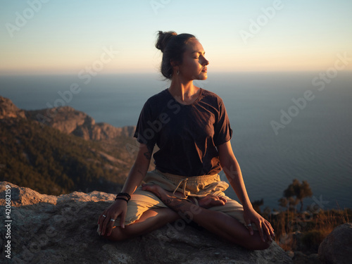 Young woman meditate on the rock photo