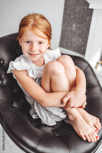 Portrait of a beautiful redhead girl snuggling up in a chair photo