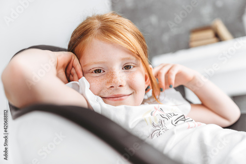 Portrait of a beautiful redhead girl relaxing in an armchair photo