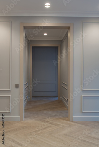 Modern and bright interior of empty cream colored corridor with herringbone parquet floor