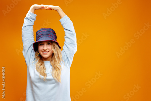 Stylish girl in panama hat dancing against yellow background