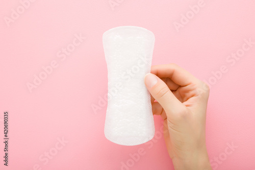Canvas Print Young adult woman hand holding new white panty liner on light pink table background