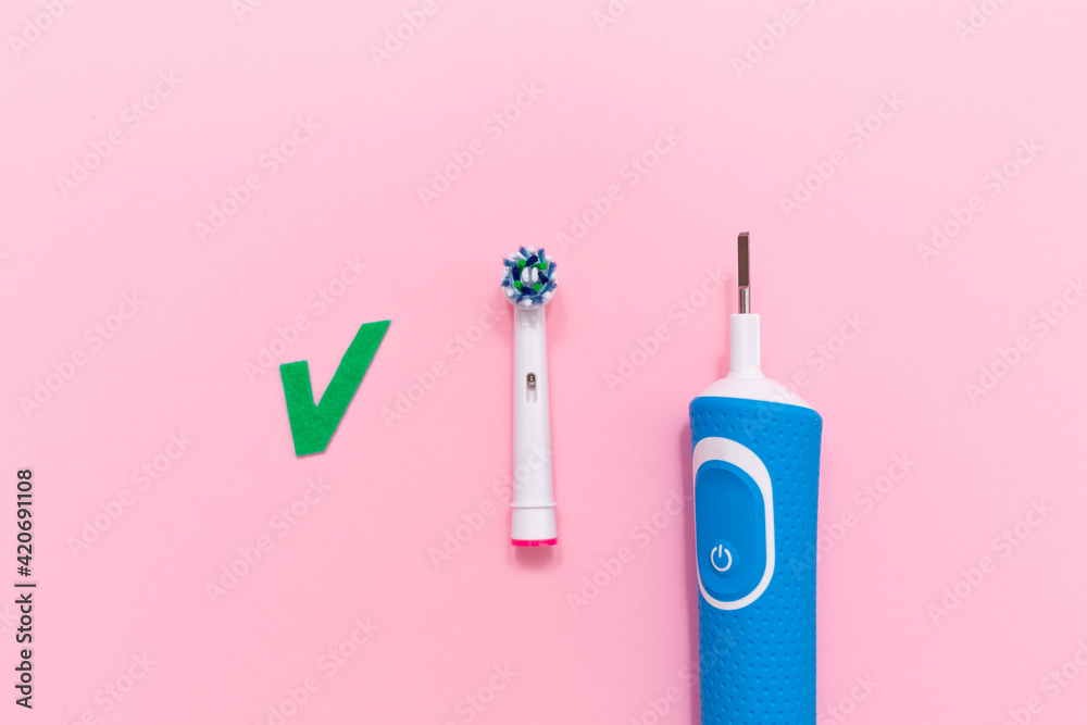 An electric toothbrush with brush head on pink background. Flat lay. Copy space. The concept of oral hygiene
