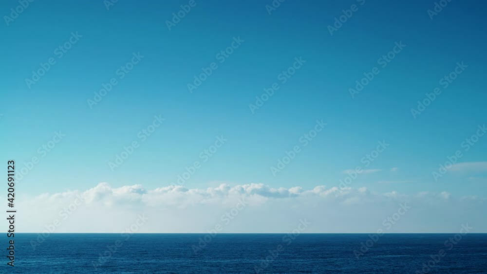 White clouds moving over mediterranean sea horizon at sunny day, Spain. Time lapse