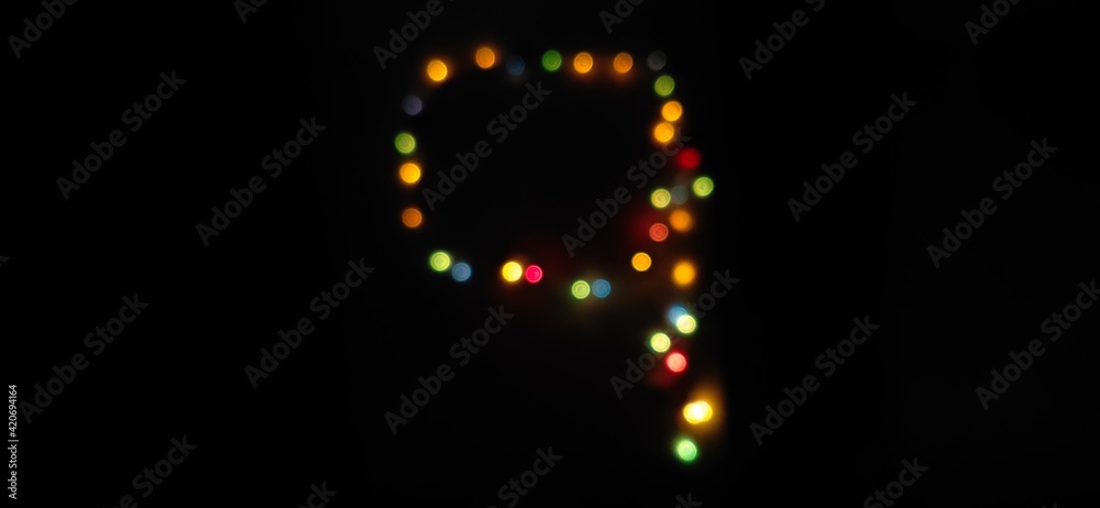 Closeup of Number nine, (9) made with multicolored blurred bokeh Christmas lights in a isolated black background with copy space