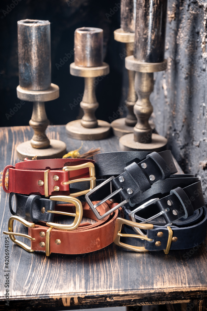 Fototapeta premium Six leather multi-coloured straps lie on a wooden table against a backdrop of vintage candles.